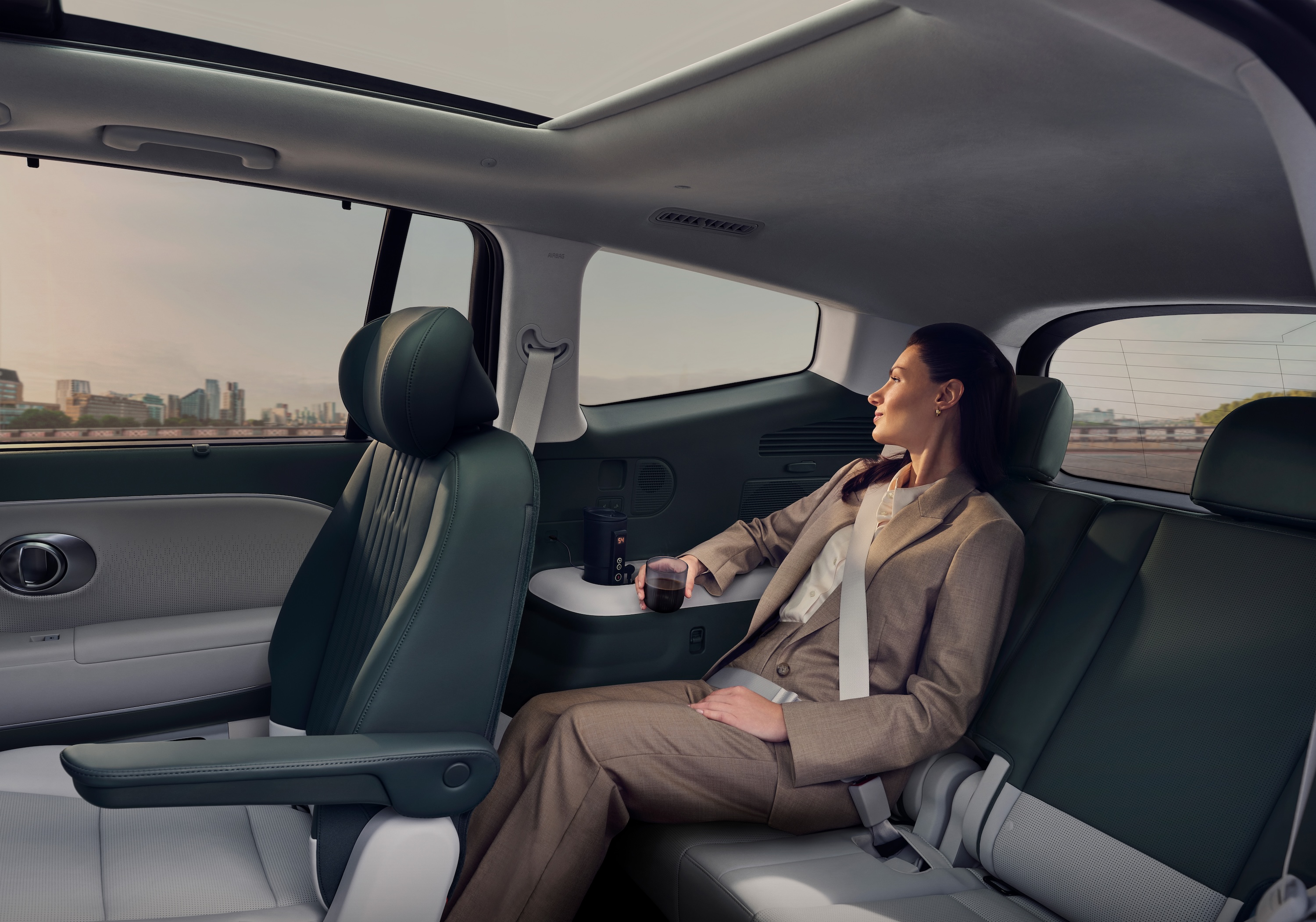 A woman relaxing in the 3rd row, drinking a coffee.